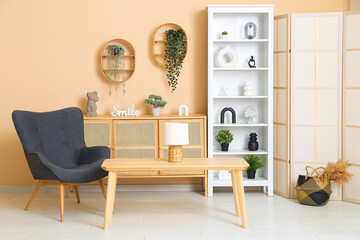 Modern shelf unit with black armchair and table near beige wall