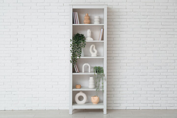 Modern shelf unit near white brick wall