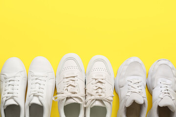 Stylish white sneakers on yellow background