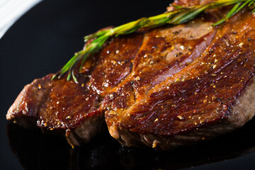 Grilled beef steak served with rosemary on black plate - obrazy, fototapety, plakaty