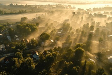 Sun shining through the fog over a small town. Perfect for depicting a serene and peaceful atmosphere. Ideal for use in travel brochures or articles about rural landscapes