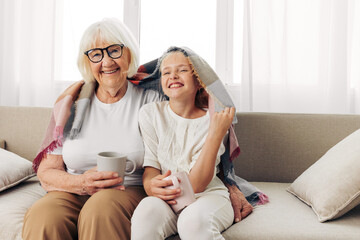 Granddaughter couch mugs love hugging child grandmother home girl sofa plaid family winter