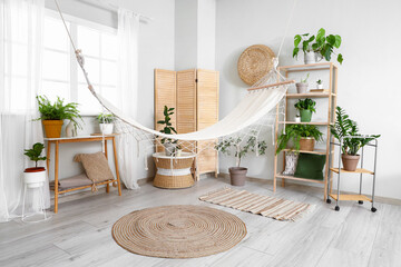 Interior of living room with green plants and hammock