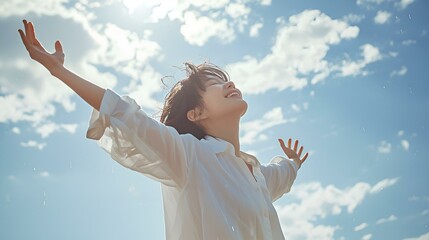A woman with her hands spread wide under a blue sky