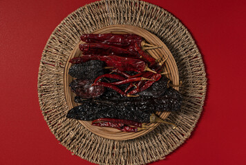 Dried Chilis on wood dish Red background Pasilla and Guajillo mexican spice