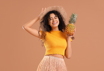 Young African-American woman with pineapple on brown background