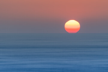 Sun setting over blue ocean