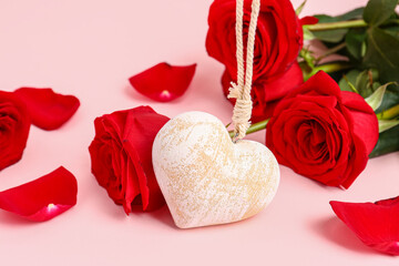 Red roses, petals and decorative heart on pink background