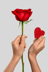 Female hands with beautiful red rose and heart on white background
