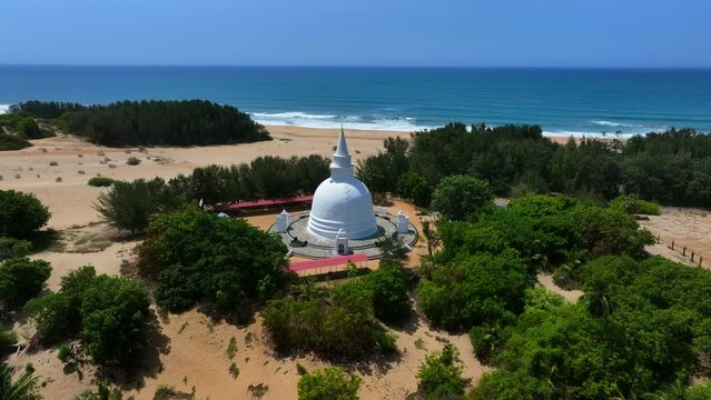 Aerial Panning Shot Of Famous Buddhist Temple At Beach By Wavy Sea On Sunny Day - Pottuvil, Sri Lanka