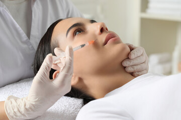 Doctor giving facial injection to young woman in clinic. Cosmetic surgery