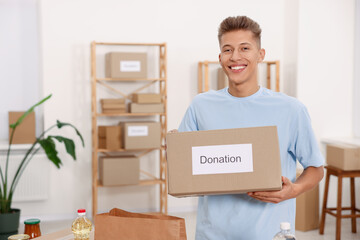 Volunteering. Happy man with donation box in warehouse