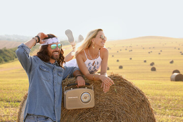 Happy hippie couple with radio receiver in field, space for text