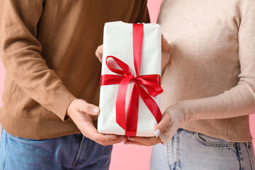 Couple with gift for Valentine's day on pink background