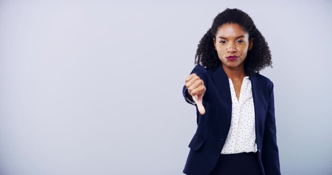 Hand, face and black woman with thumbs up, down or choice, change or conflict in studio on grey background. Emoji, vote and portrait of female entrepreneur with finger, review or business rating