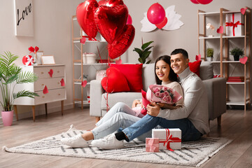 Young couple with bouquet of roses at home on Valentine's day