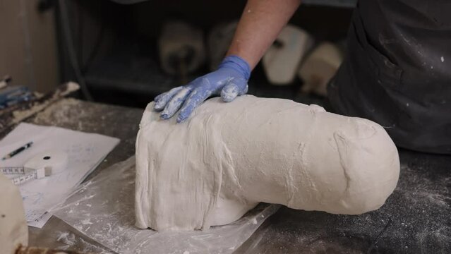 Plaster crafting, Workspace innovations, Workspace organization. Man, in professional setting, creating plaster version of prosthetic leg mold designed for hip disarticulation.