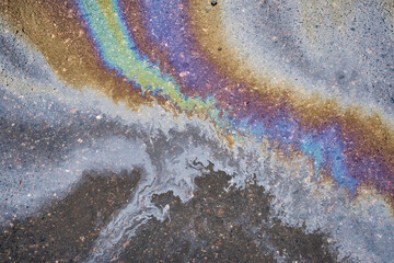 Petroleum fuel spilled on wet asphalt, abstract background