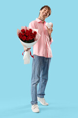 Handsome young man with bouquet of roses and fabric heart on blue background. Valentine's day...