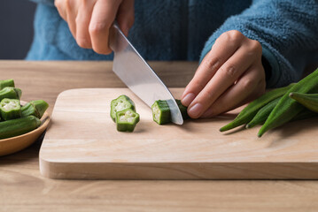 Green okra cutting on wooden board, homemade cooking - obrazy, fototapety, plakaty