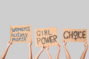 Female hands holding cardboard pieces with text CHOICE, GIRL POWER and WOMEN'S HISTORY MONTH on...