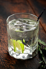 Pure still water with lemon and ice in a glass on a wooden background.