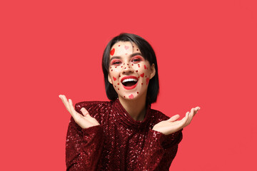 Beautiful happy young woman with creative makeup for Valentines Day on red background