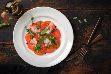 Tomato salad cut into slices with parmesan, arugula and balsamic vinegar. Vegetarian Italian antipasti, top view and copy space