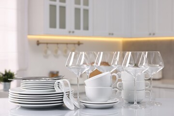 Set of clean dishware, glasses and cutlery on table in kitchen