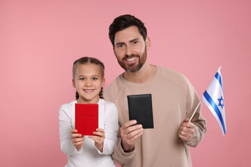 Immigration. Happy man with his daughter holding passports and flag of Israel on pink background