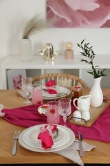 Color accent table setting. Glasses, plates, pink napkins and vase with green branch in dining room