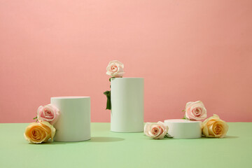 Fresh roses are decorated around the cylindrical platforms on a pink background. Spacious space for...