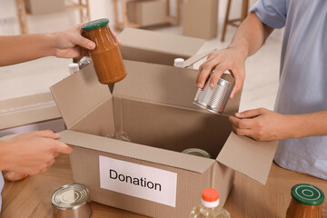Volunteers packing food products at table indoors, closeup