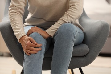 Mature woman suffering from knee pain indoors, closeup. Rheumatism symptom - obrazy, fototapety, plakaty