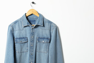 Naklejka premium Hanger with denim shirt on white wall, space for text