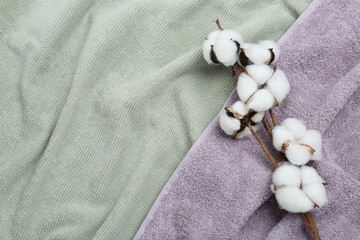 Cotton flowers on soft towels, top view. Space for text