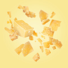Tasty parmesan cheese falling on light golden background