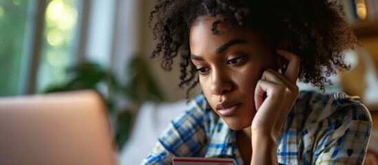 Worried black woman reviews credit card spending. - obrazy, fototapety, plakaty