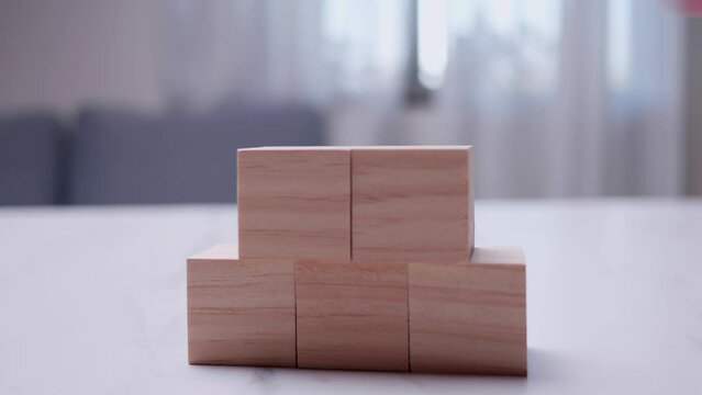 Taking a close-up shot of an individual stacking wooden blocks on top of each other on a table.