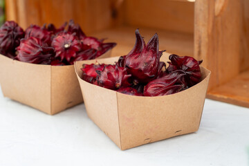 Cardboard square boxes of organic hibiscus sabdariffa or dried roselle flowers for sale. The...