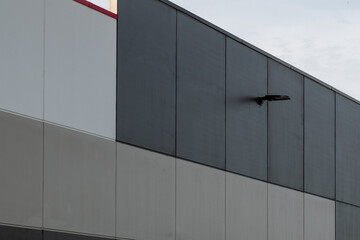 Commercial external vertical metal composite panels on a large building with clouds in the background. The durable metal composite panels are various shades of grey color on the modern building.