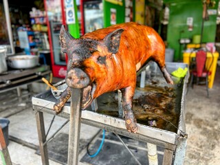 Views of a whole fire roasted pig for sale in a food stall in Ecuador which specializes in Cascarita or pig skin roasted over an open fire