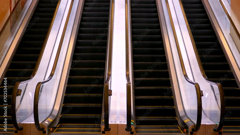 Aufkleber an escalator with black steps, ascending into a bright light, flanked by reflective metallic handrai