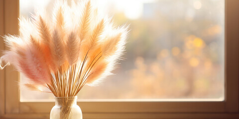 Soft pampas grass in a clear vase on a windowsill, bathed in the golden light of autumn