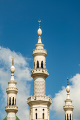 Fototapeta na wymiar The mosque tower building with a bright blue sky background with white clouds makes it beautiful.