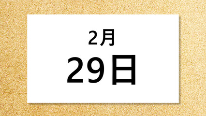コルク背景の上に置いた2月29日の文字入り白紙_ワイド