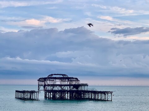 Ruin of West Pier off coast of Brighton in Sussex, UK. Calm seascape and pebble beach in England in summer. 
