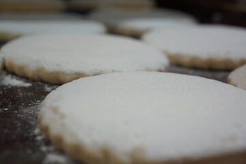 Flat Spanish polvorones with white powder, in tray, macro, well lit