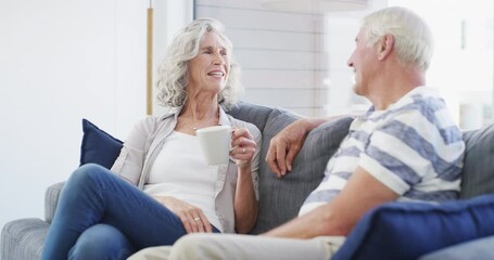 Coffee, conversation and senior couple on a sofa relax, bond and enjoying retirement in their home together. Love, speaking and old people in a living room with tea, communication and weekend freedom - Powered by Adobe