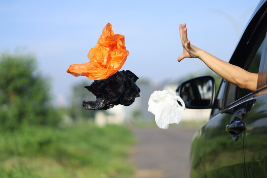 female driver's hand throwing plastic waste on the highway through the car window.  bad behavior and habits that damage the environment.